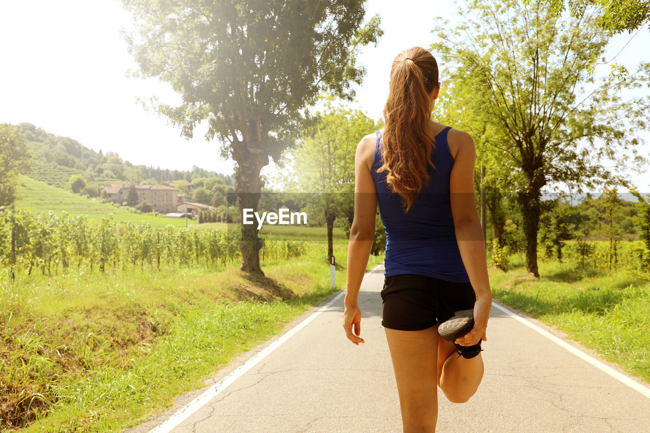 Rear view of woman exercising on road