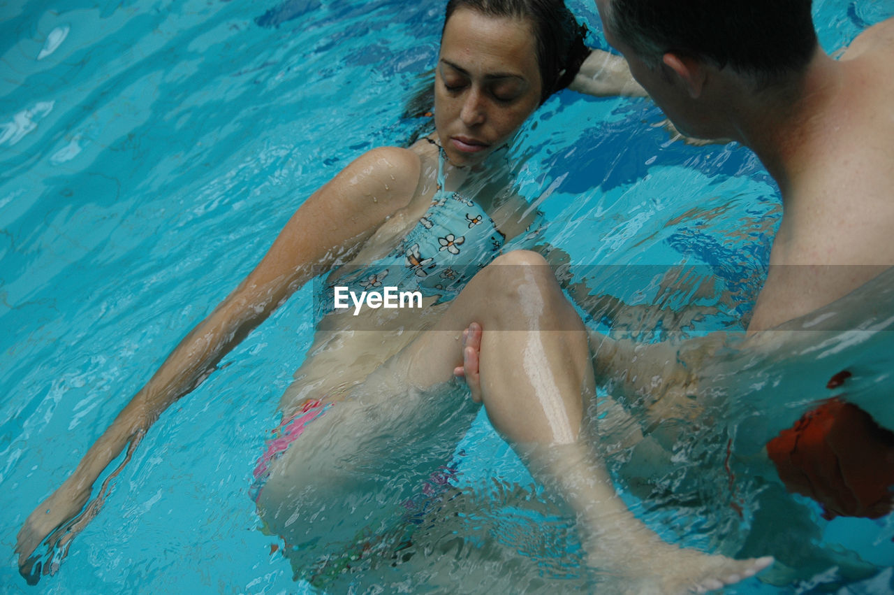 Shirtless man picking woman from swimming pool