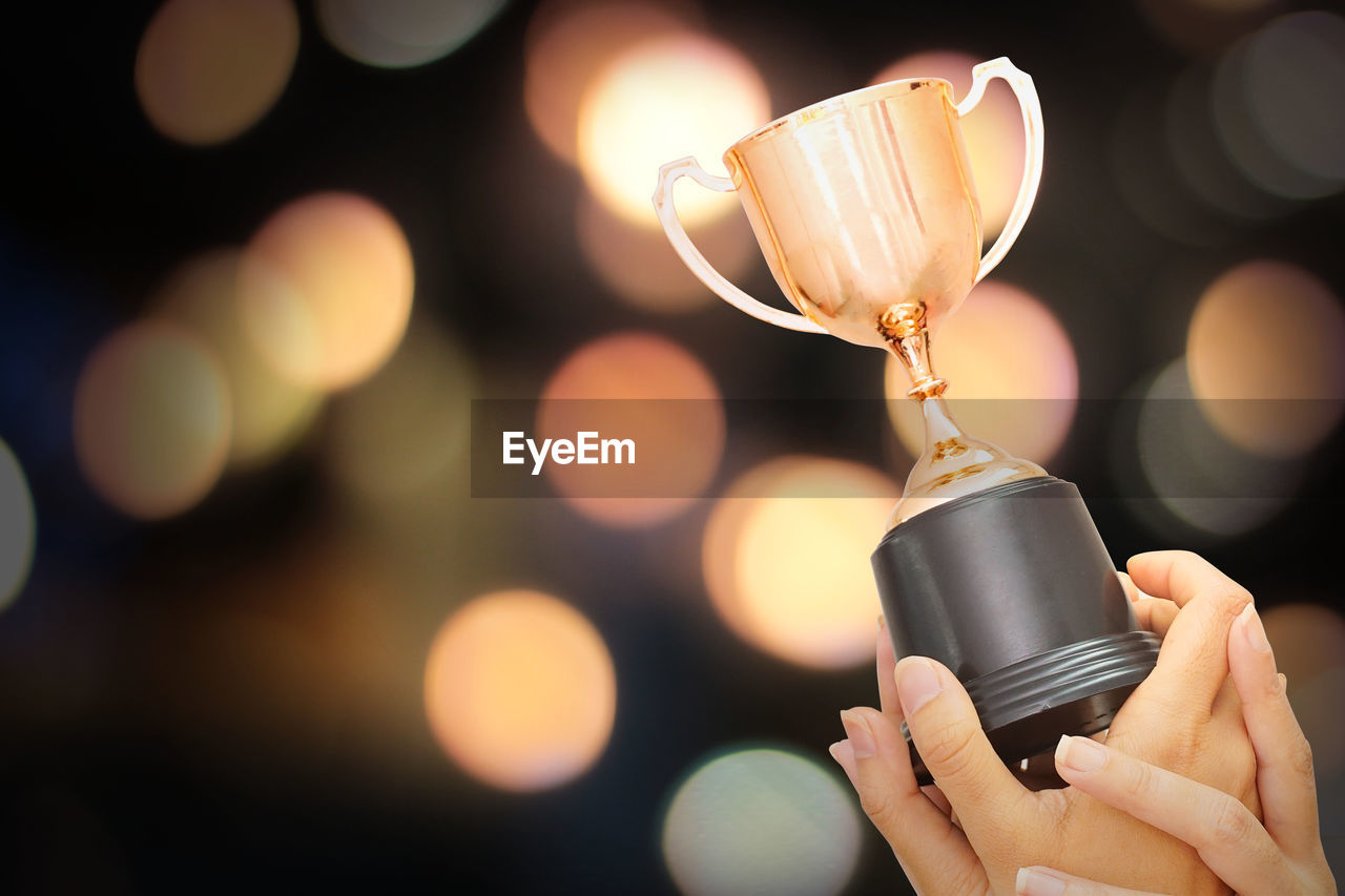 Trophy on winner hand with bokeh background