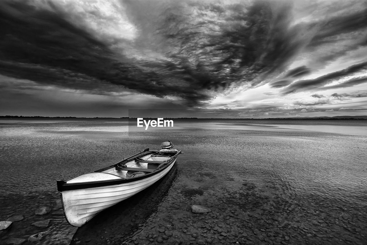 BOAT MOORED ON SEA AGAINST SKY