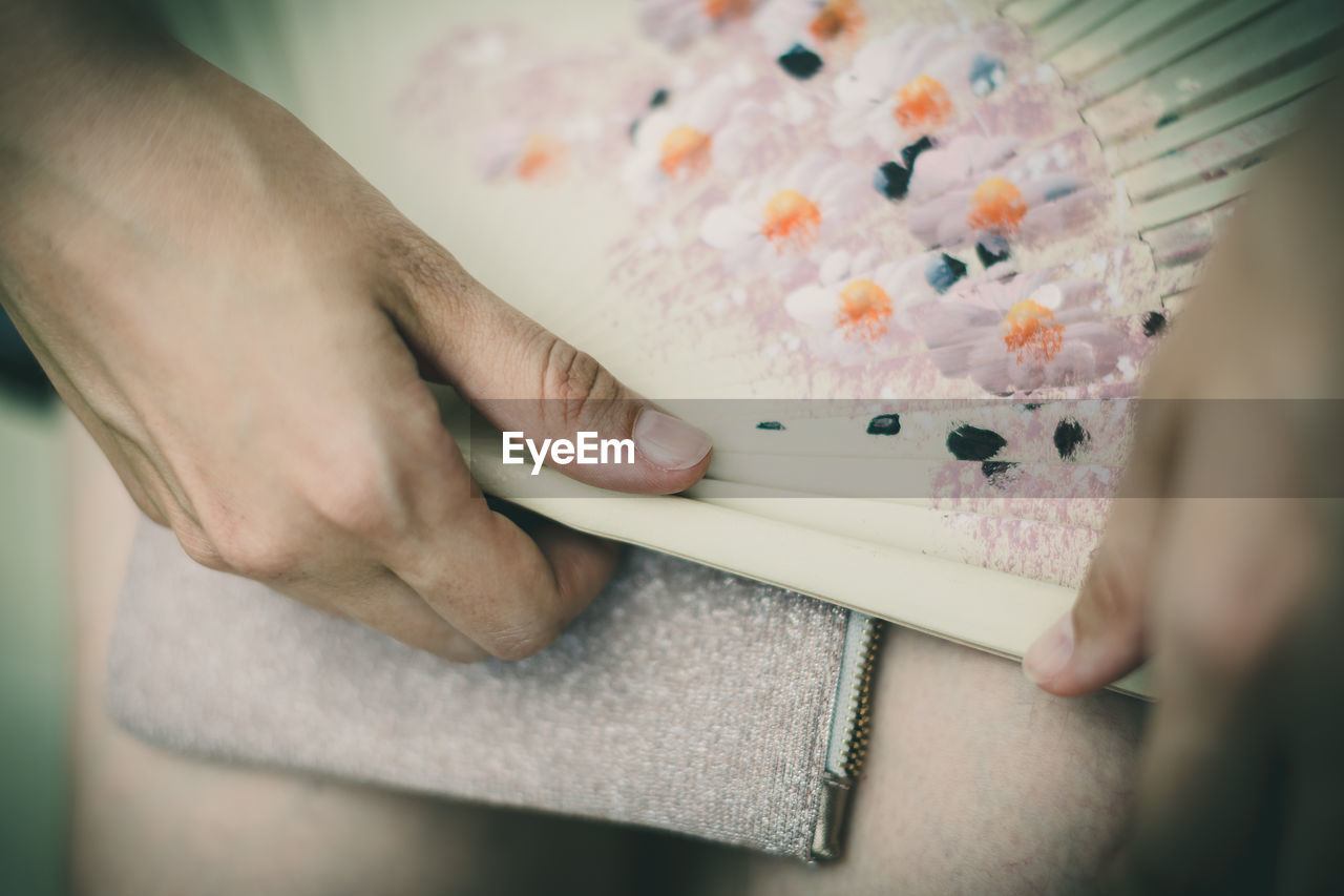 Cropped hands of woman holding folding fan