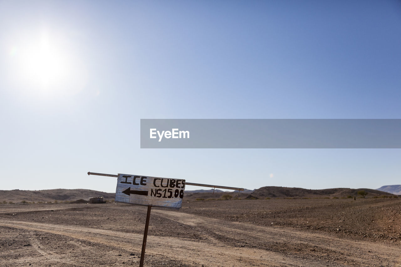 Road sign on desert against clear sky