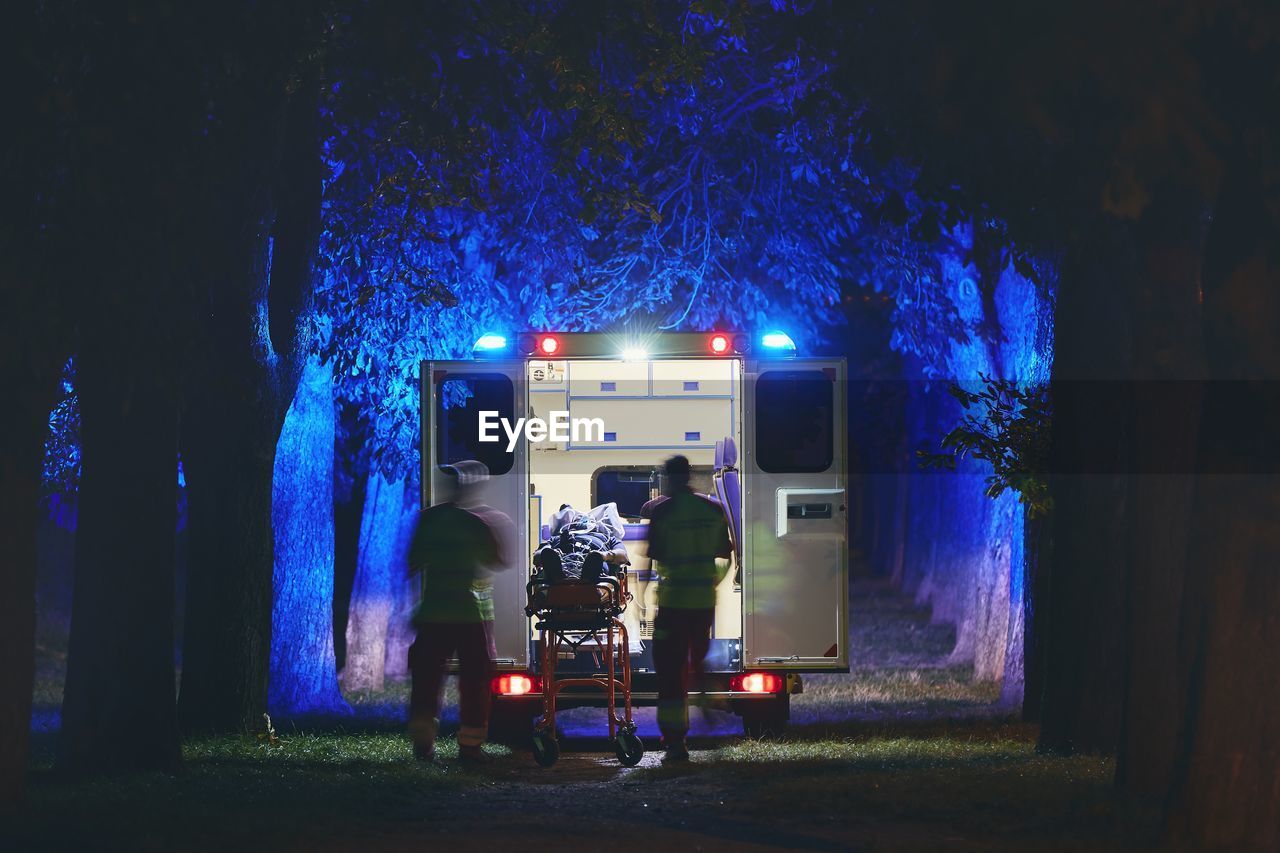 Doctors and patient by ambulance in forest at night