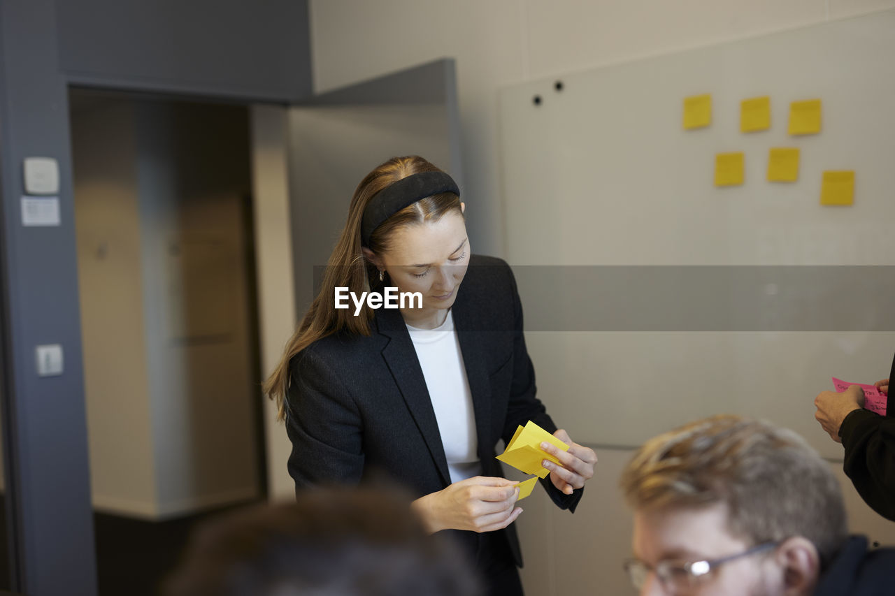 Woman holding post its during business meeting