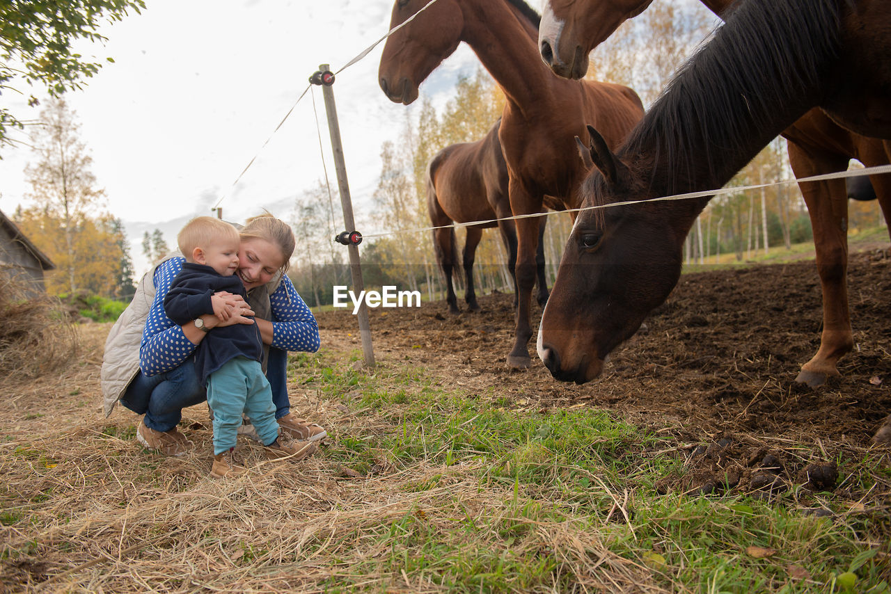 Mother and son playing with horses in ranch