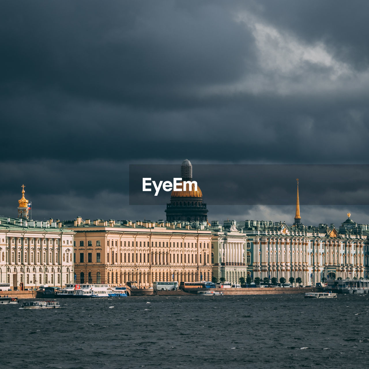 View of city by sea against storm clouds