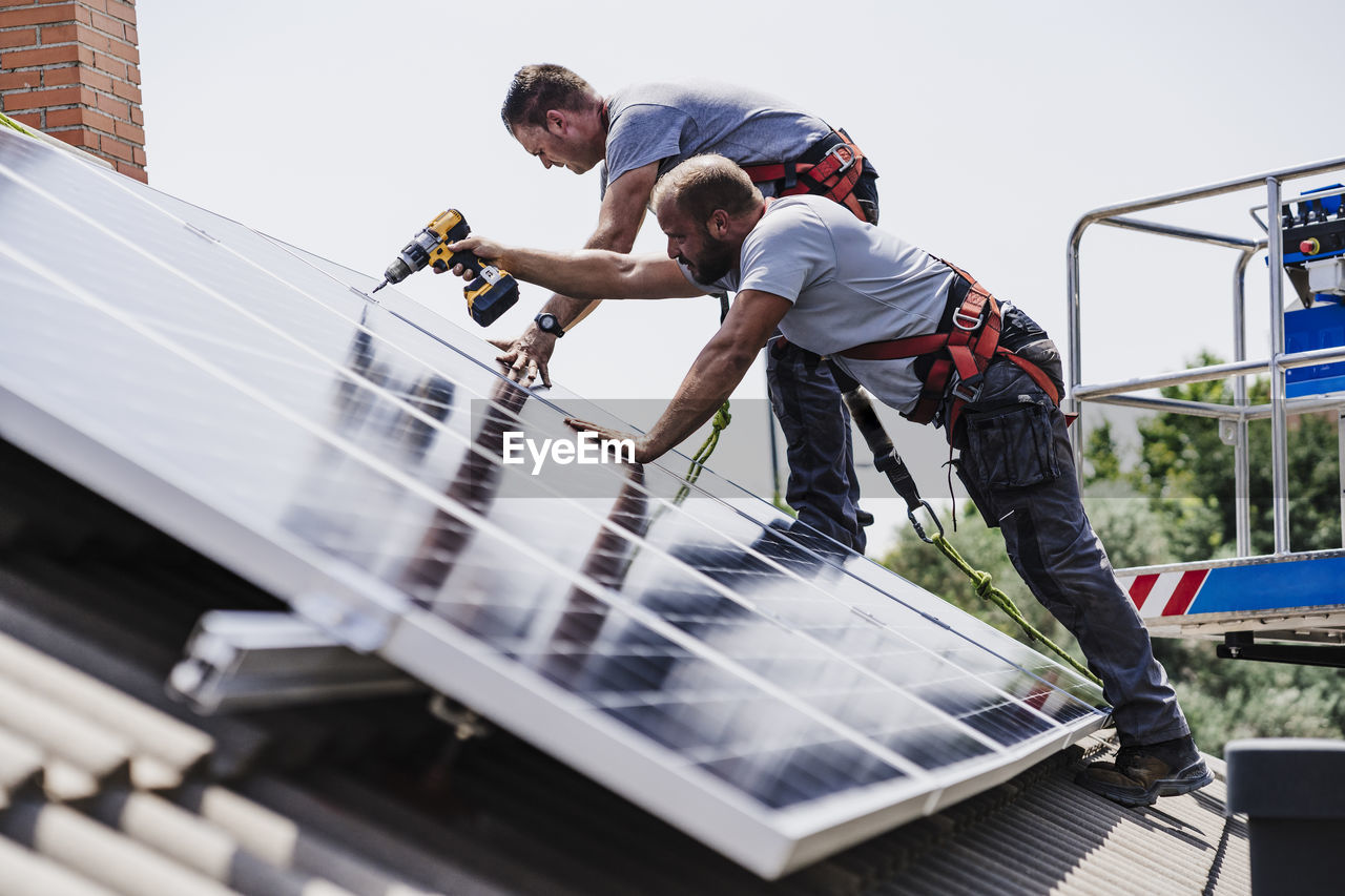 Craftsmen installing solar panels on house rooftop