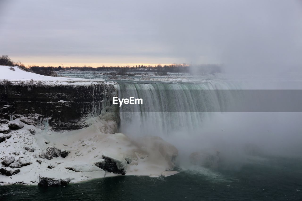 Scenic view of waterfall against sky