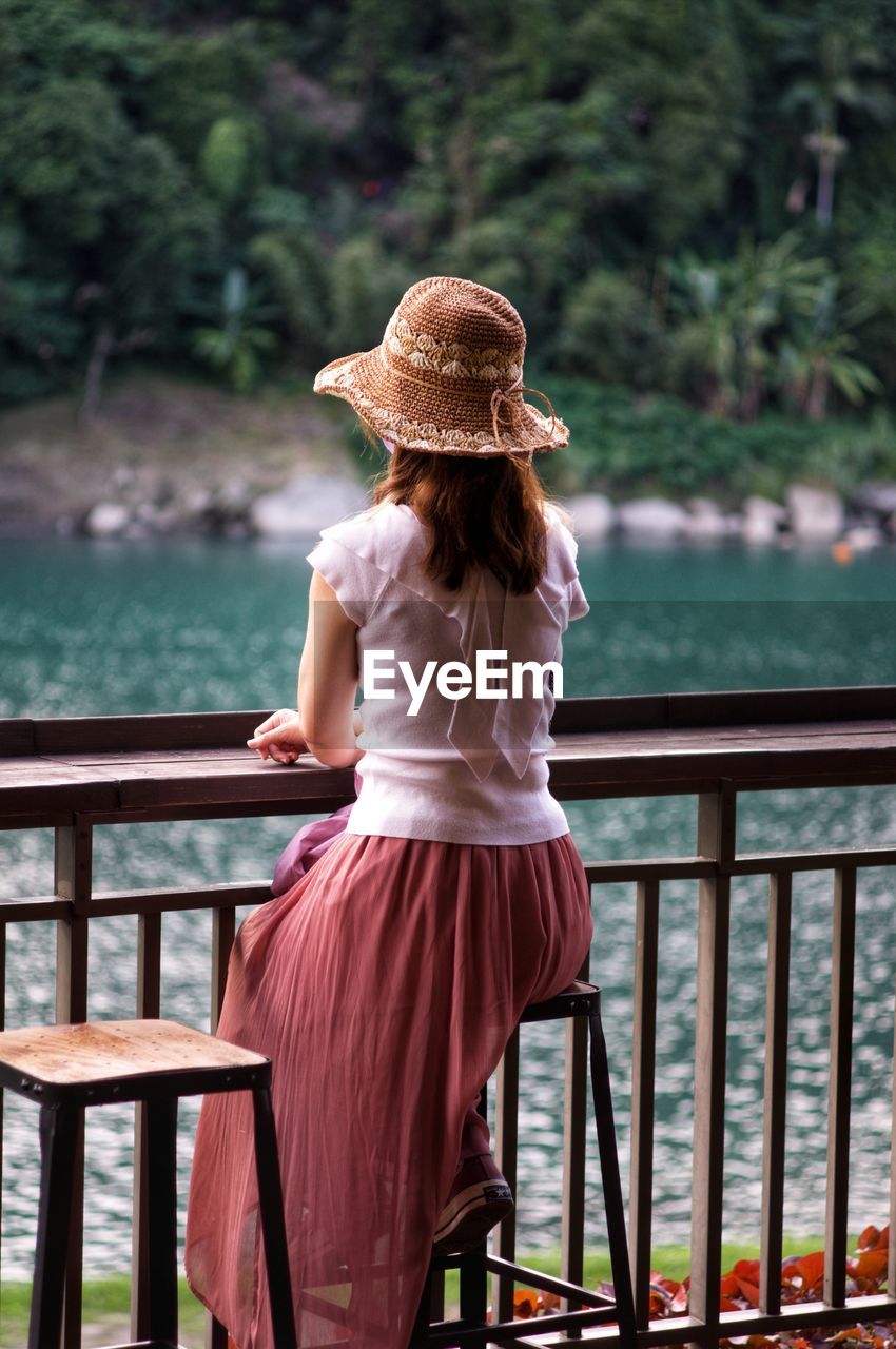 Side view of woman sitting on railing