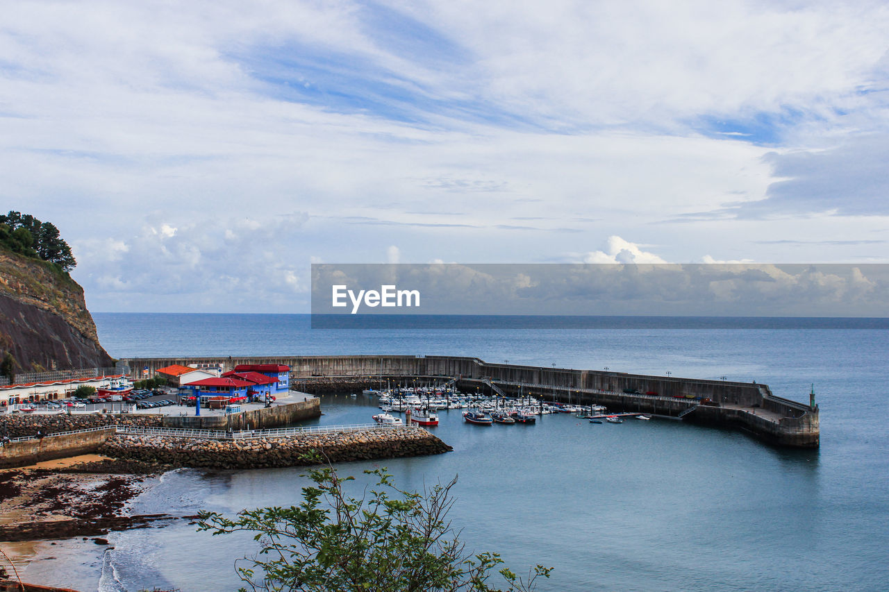 High angle view of boats moored at harbor against cloudy sky