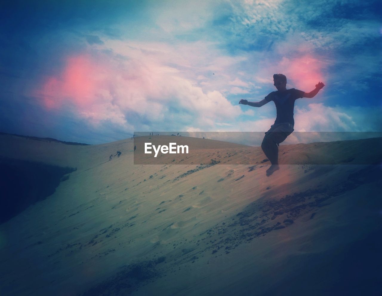 Man jumping on sand against sky