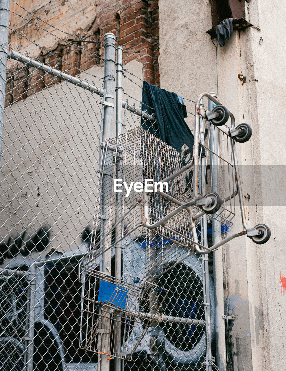 Close-up of clothes hanging on metal fence against building.