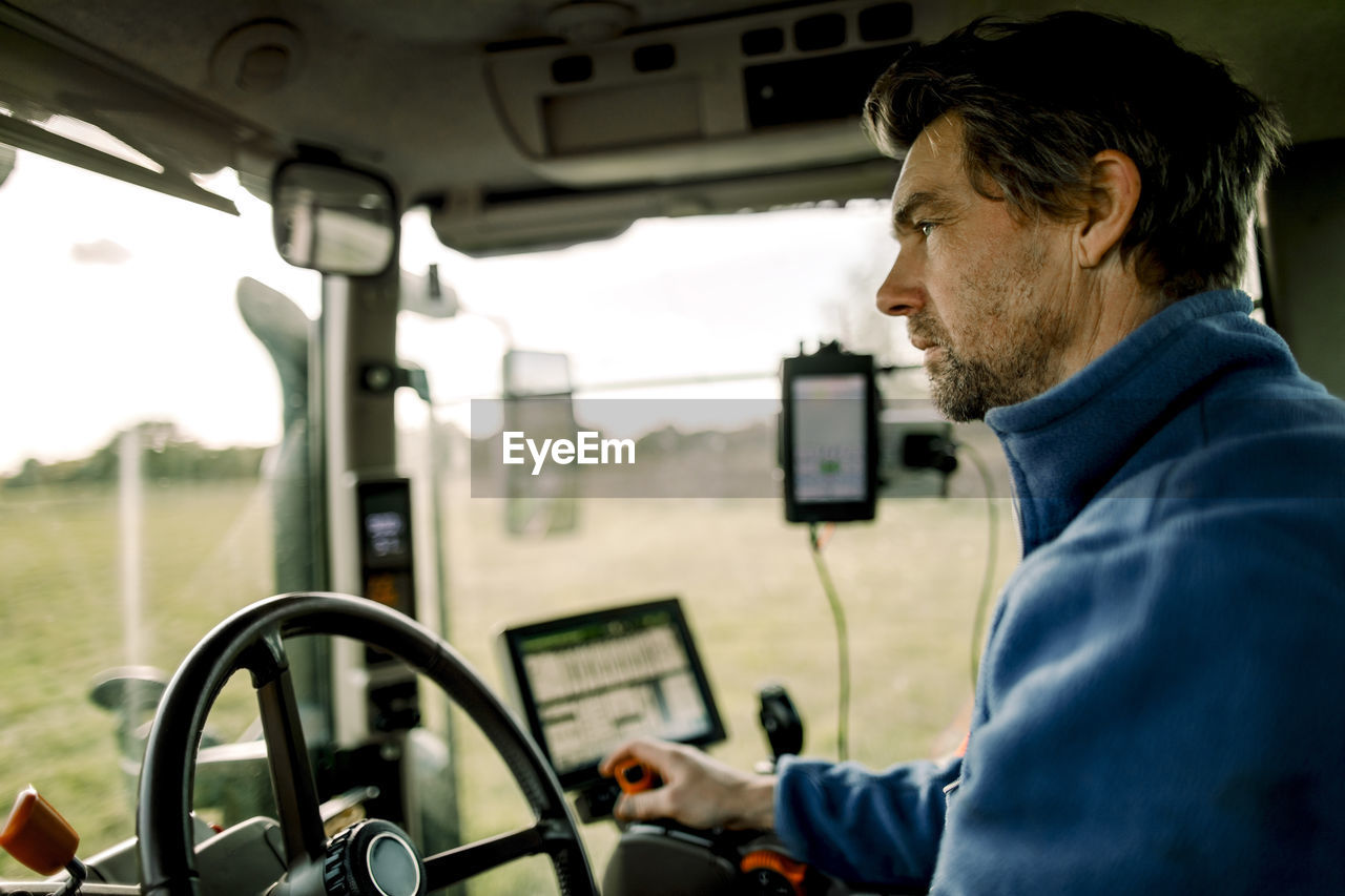 Mature farmer driving tractor on field