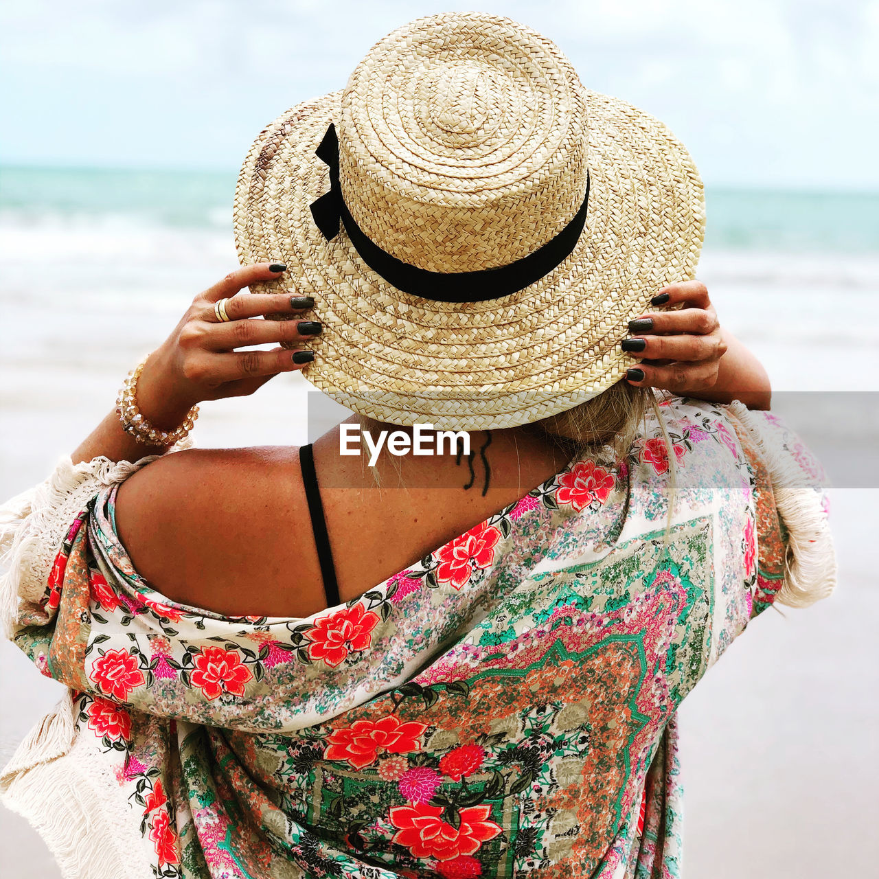 Rear view of woman wearing hat standing on beach