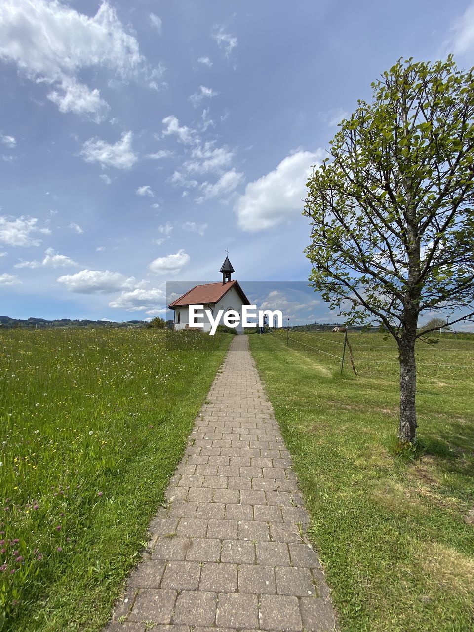 FOOTPATH AMIDST FIELD AND BUILDING AGAINST SKY