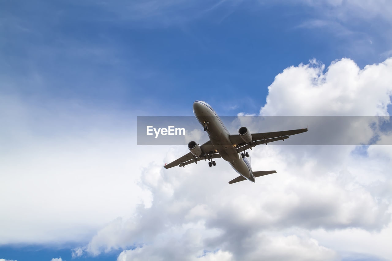 LOW ANGLE VIEW OF AIRPLANE FLYING AGAINST CLOUDY SKY