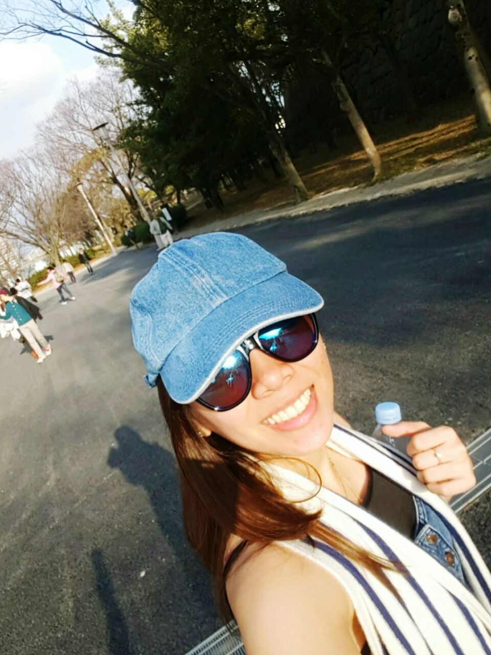 Close-up of happy woman wearing cap standing on street against trees