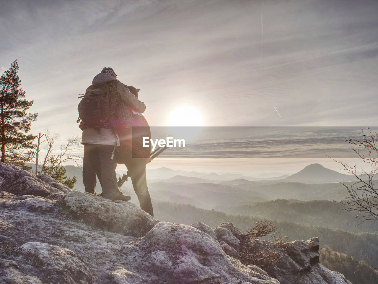 Man photographer and woman traveler photographing with the camera on the tripod. two people hugging