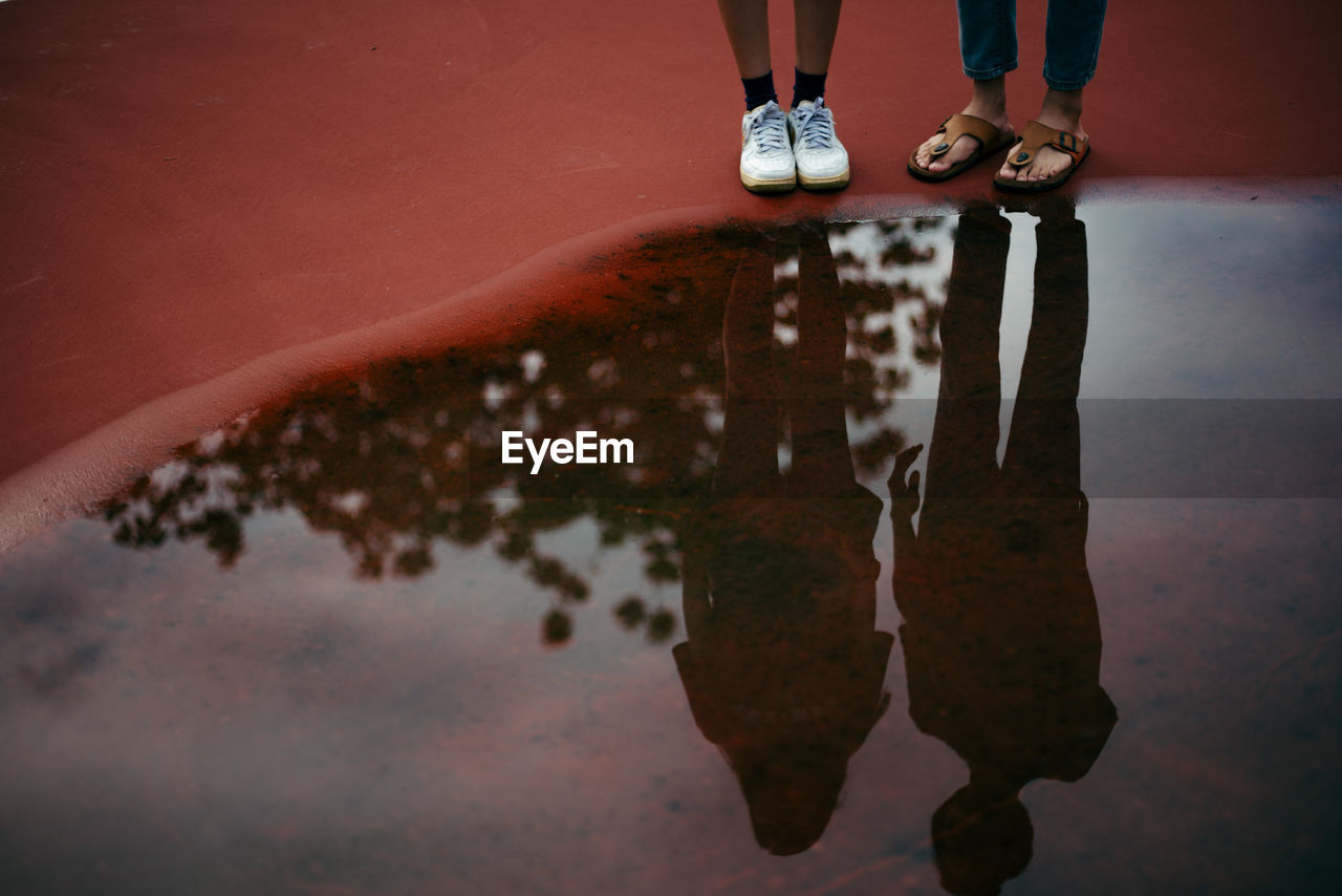 Low section of friends standing by puddle