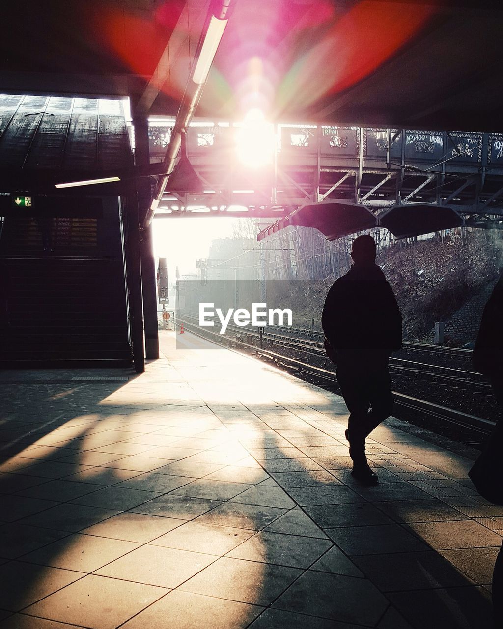 Silhouette man walking on railroad station platform