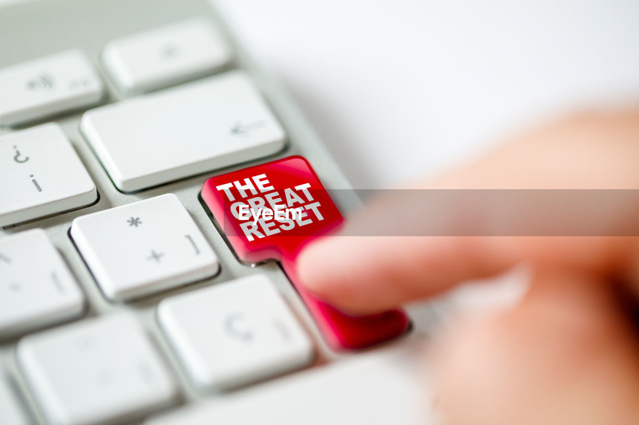 Keyboard button pressed by a finger representing the great reset concept