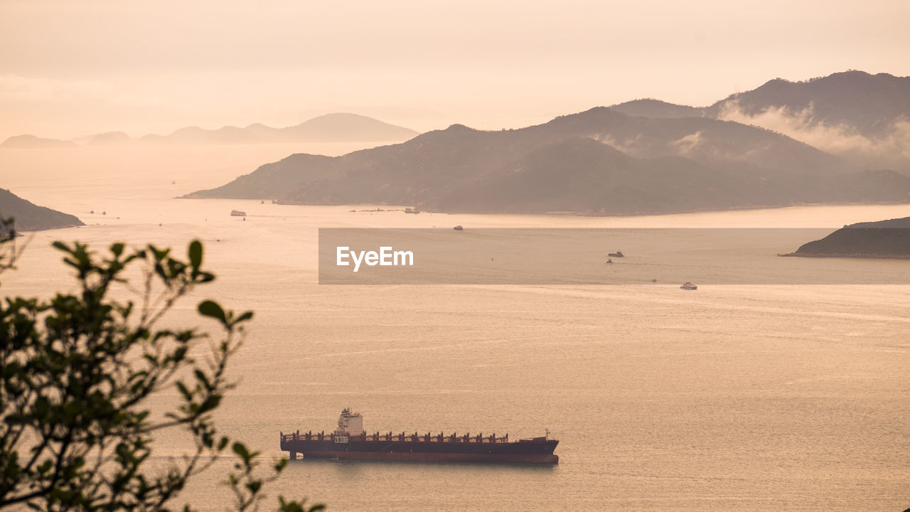 Hong kong cargo ship nuatical transportation  vessel ocean beautiful sunset mountain landscape