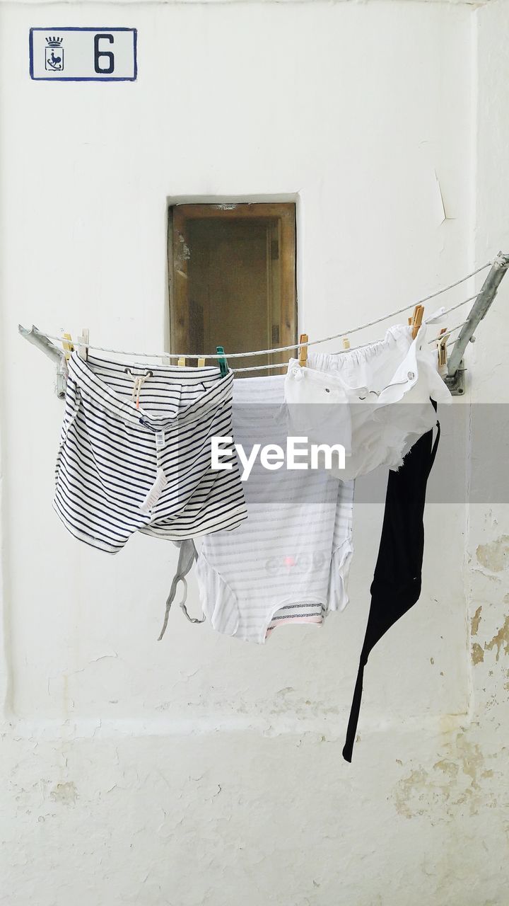 CLOTHES DRYING ON CLOTHESLINE AGAINST WHITE BACKGROUND