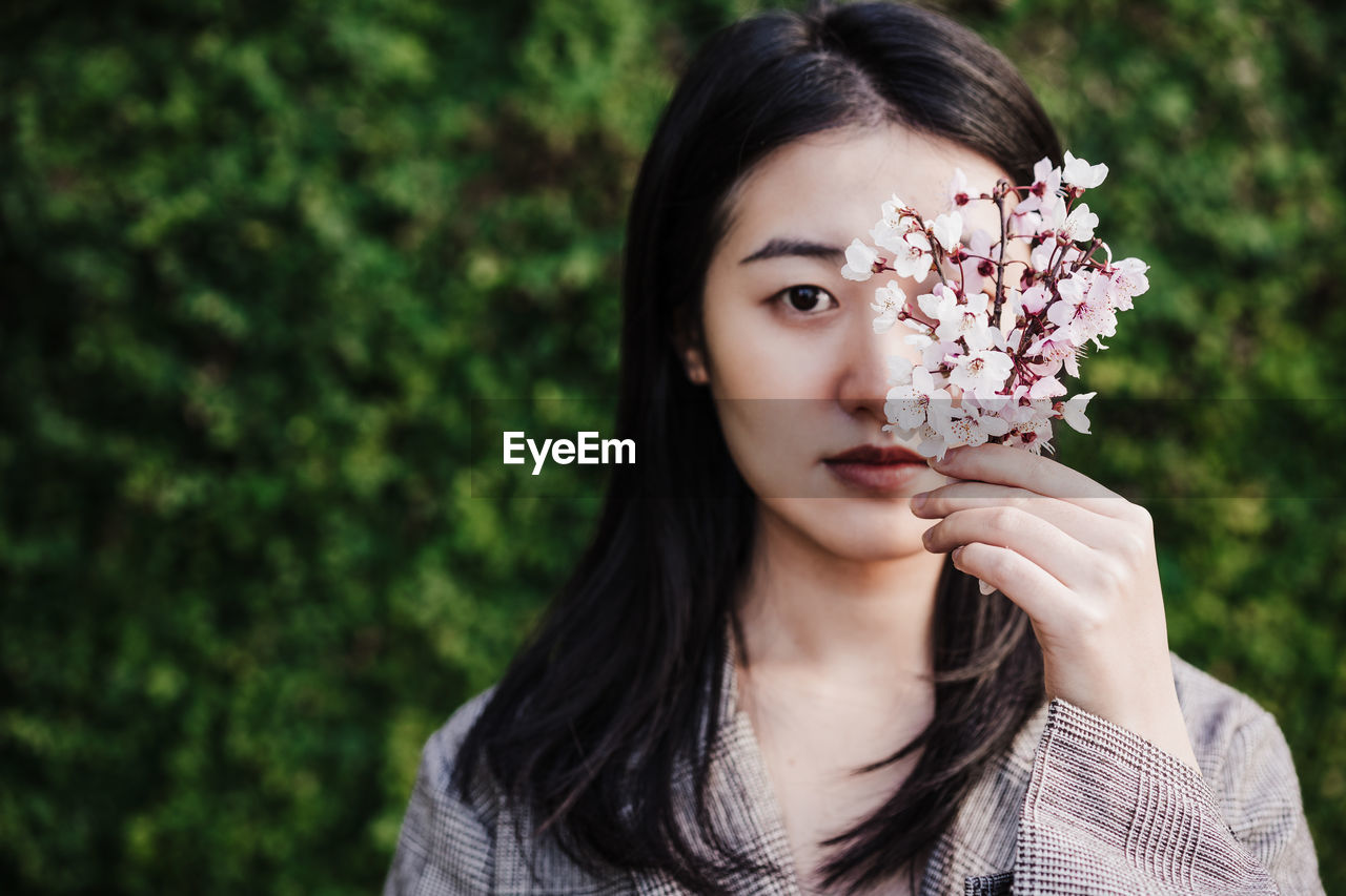 Beautiful chinese asian woman holding almond tree flowers.spring. selective focus on flowers