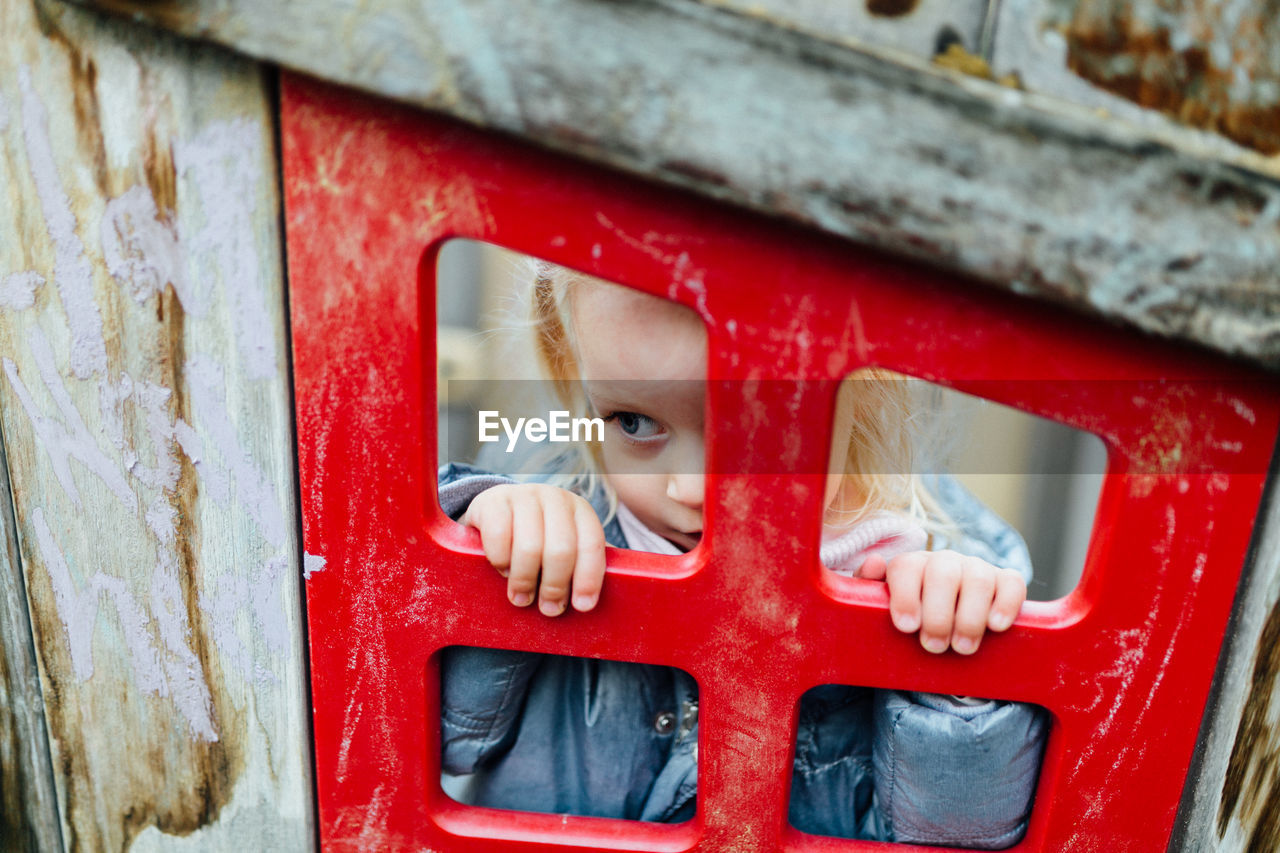 High angle view of cute girl looking through window at playground