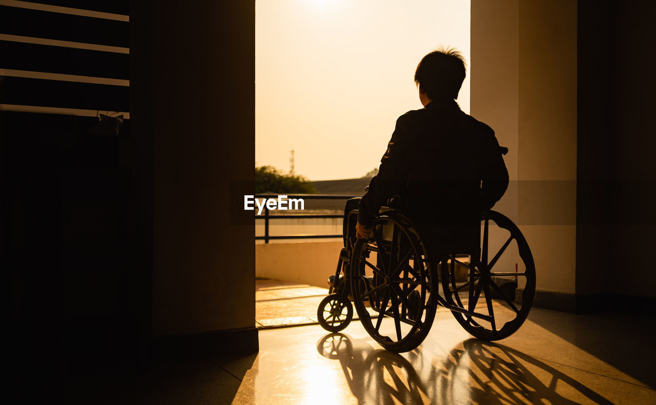 Rear view of silhouette man sitting in wheelchair