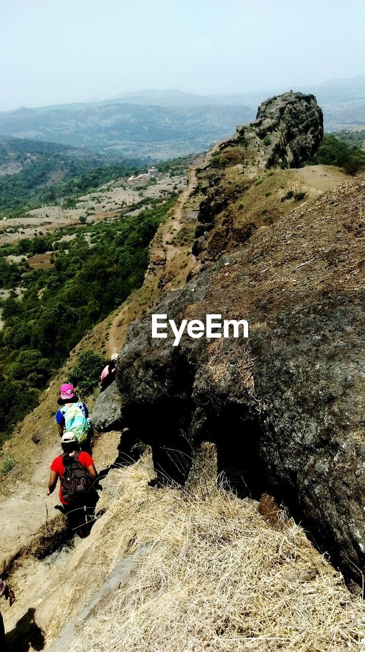 MAN ON CLIFF AGAINST SKY