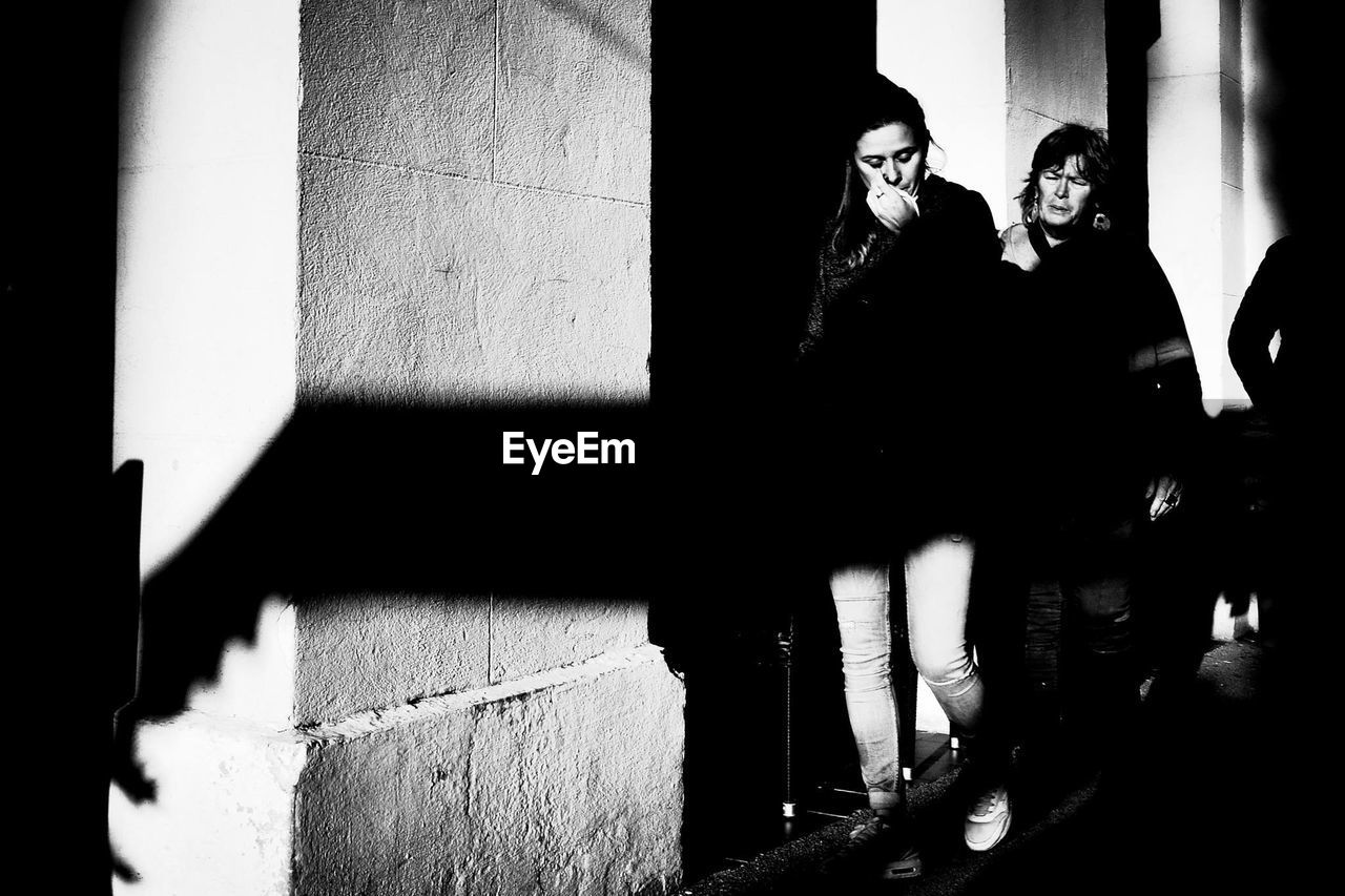 YOUNG COUPLE STANDING AGAINST WALL IN ROOM