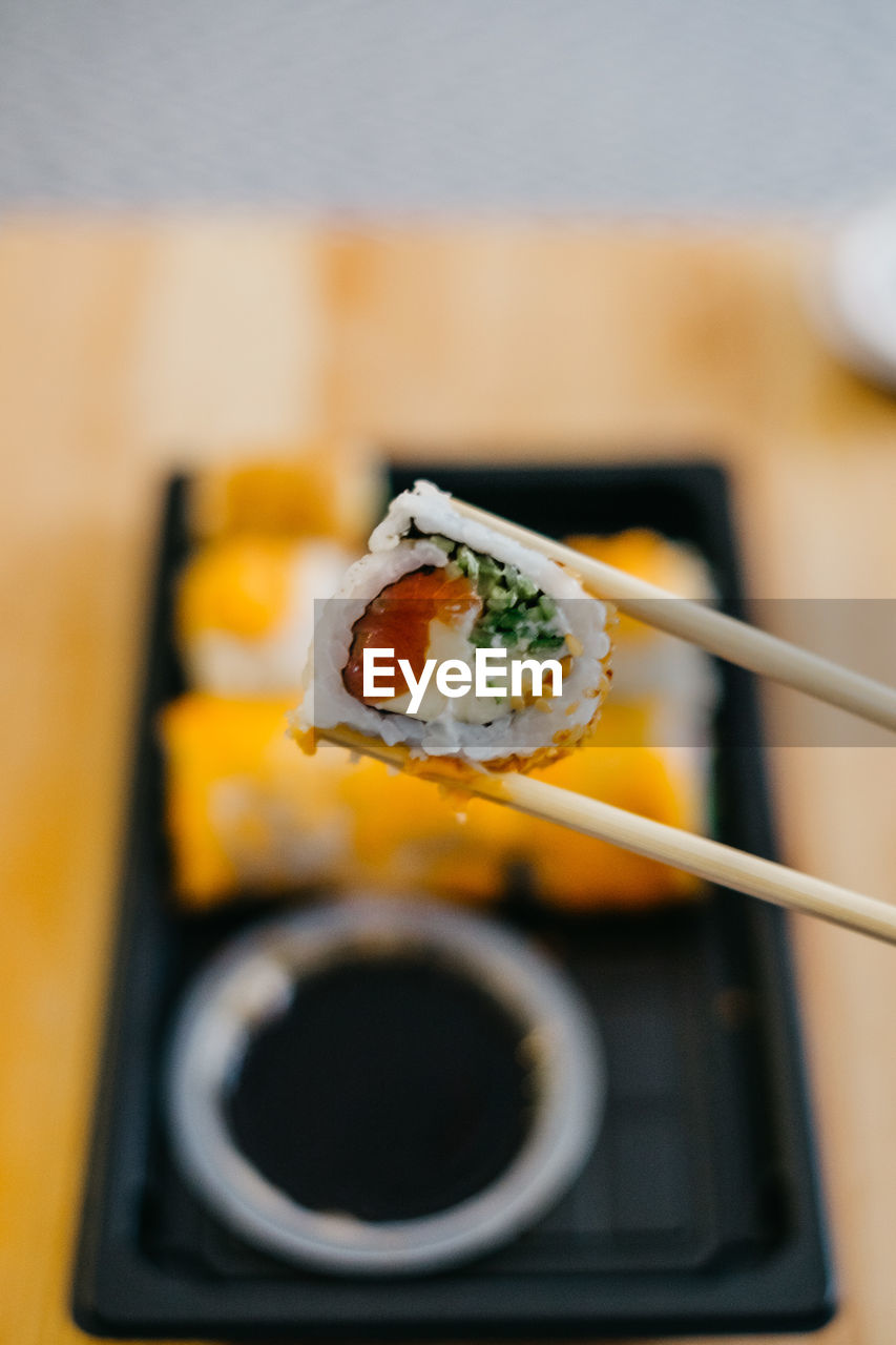 Close-up of sushi in chopsticks in plate