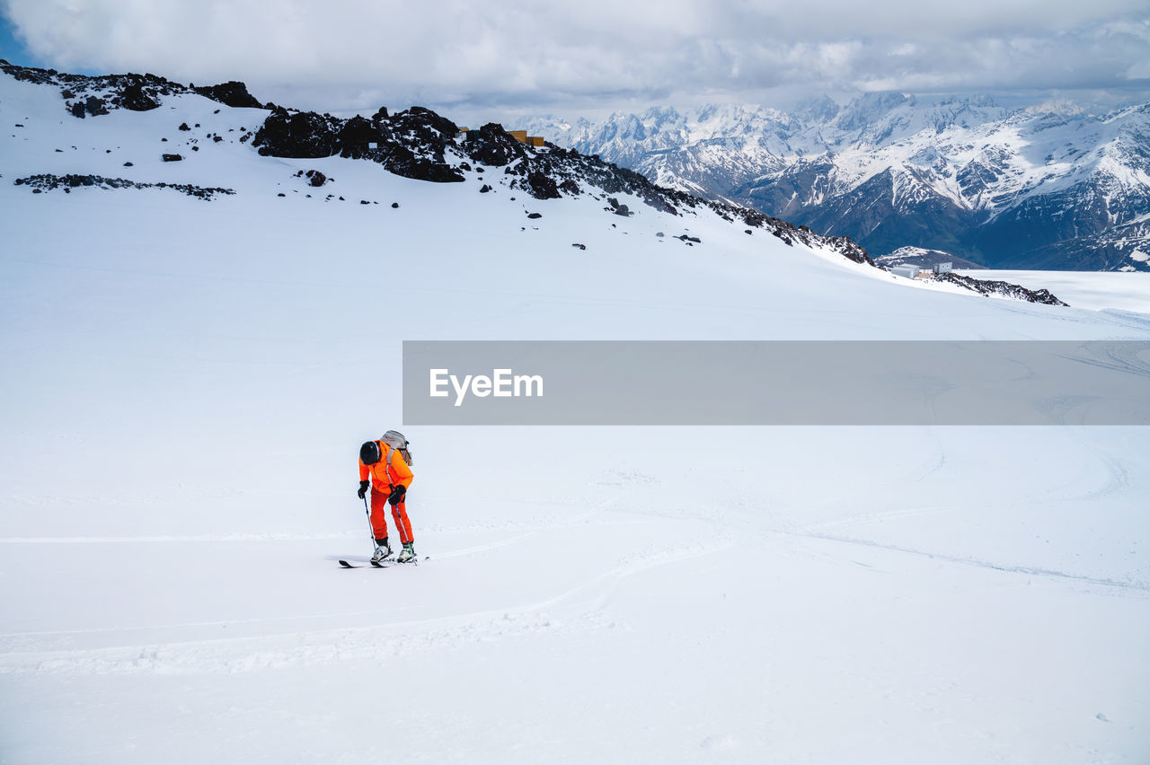 Man on skis climbs up the snow on a background of mountains