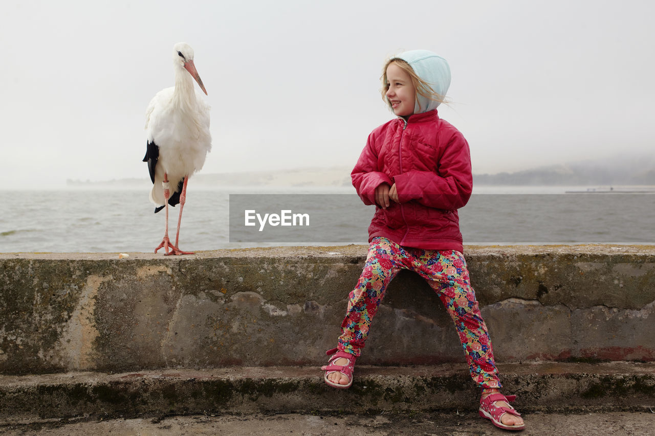 REAR VIEW OF WOMAN WITH SEAGULL AGAINST SEA