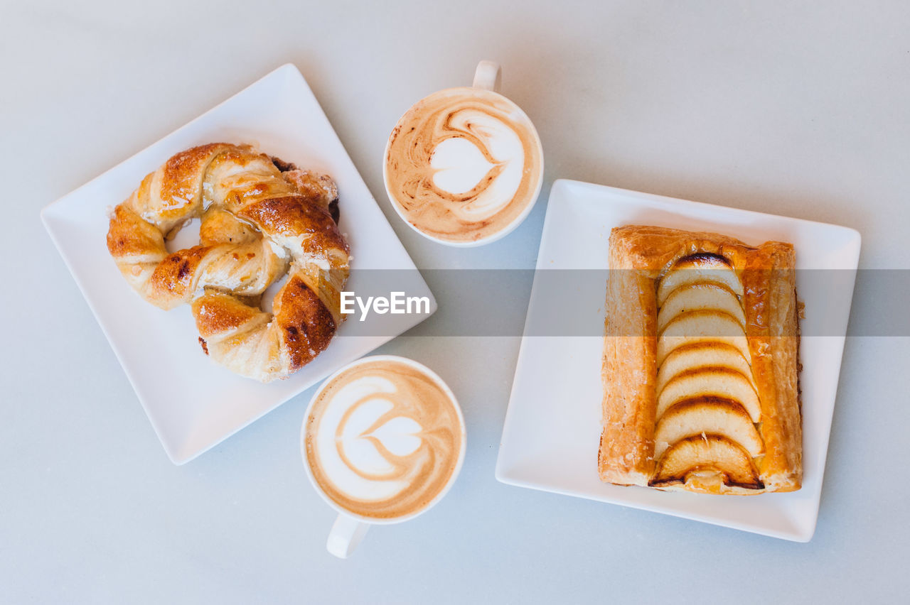 Directly above shot of snacks with cappuccinos served on table