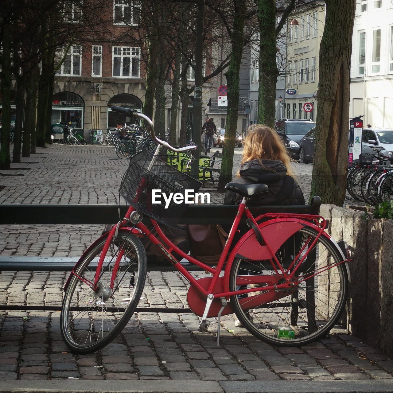 Bicycle on cobblestone street with woman sitting on bench