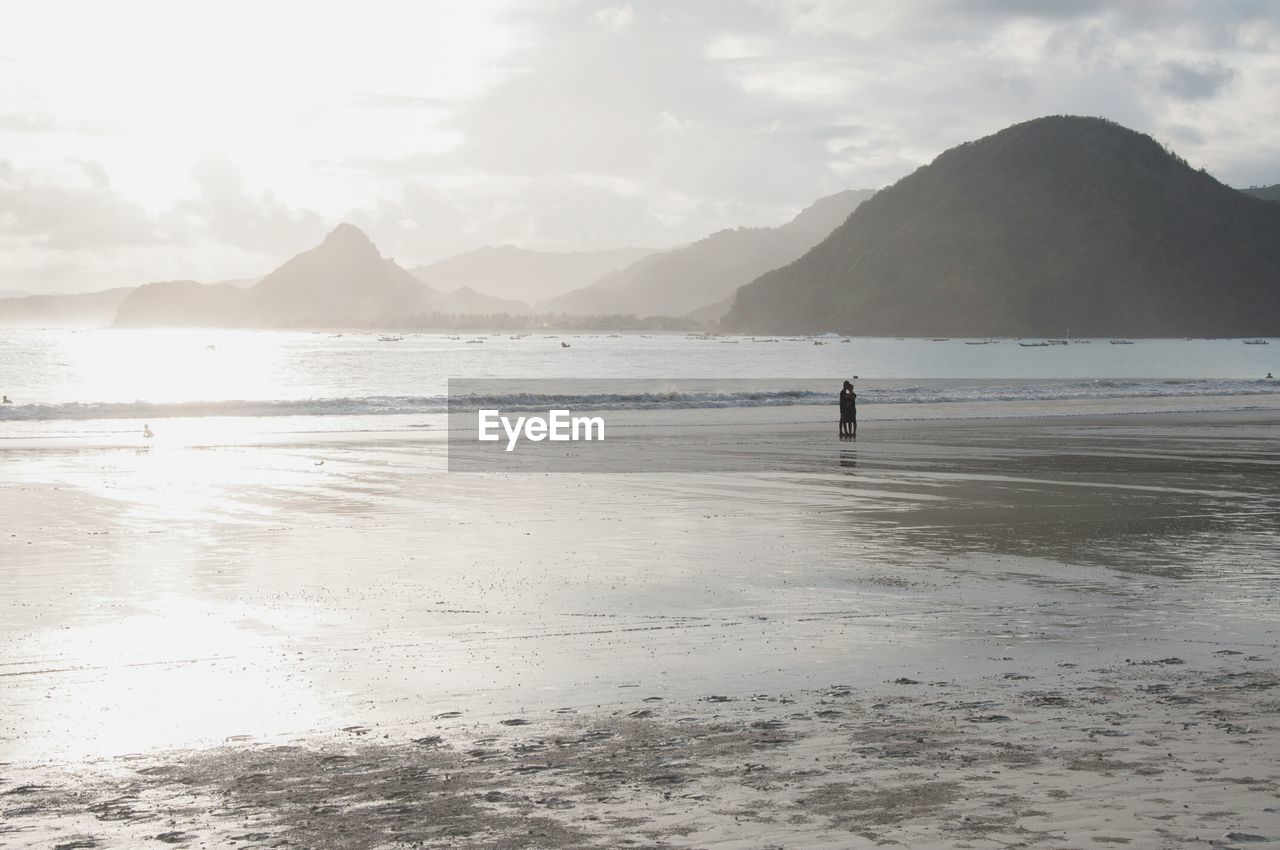 People standing at beach against sky