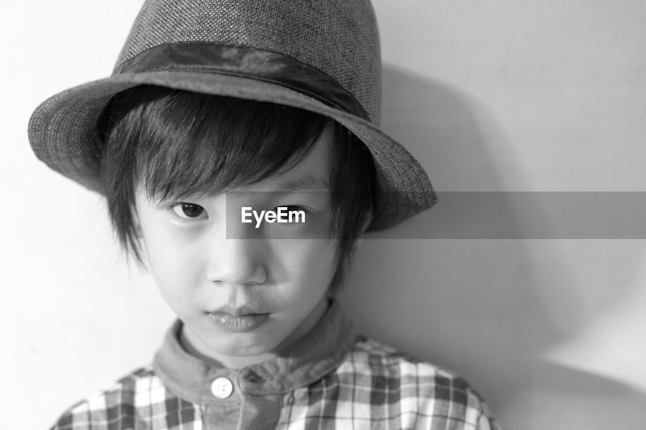 Portrait of cute boy wearing hat against wall