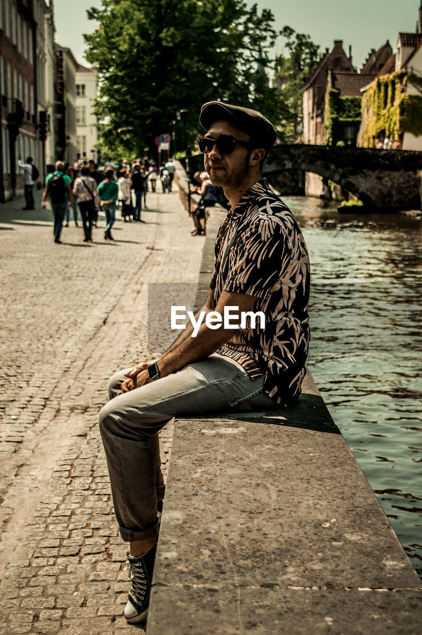 Full length of man sitting against canal