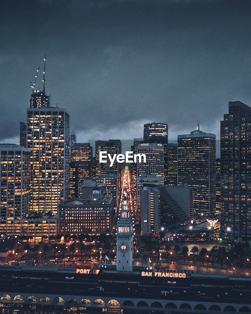 Illuminated buildings against cloudy sky at dusk