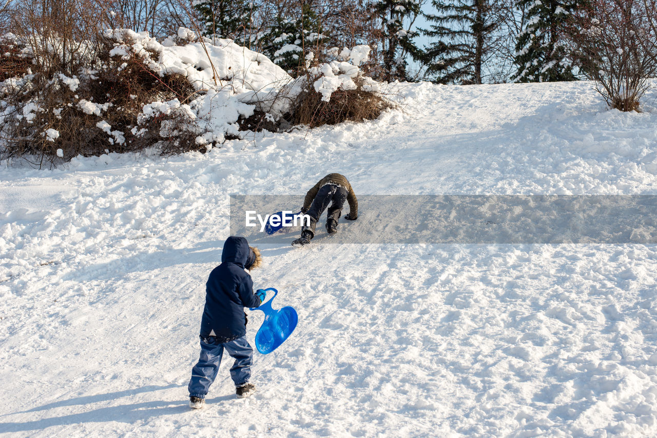 Rear view of boys playing on snow covered land