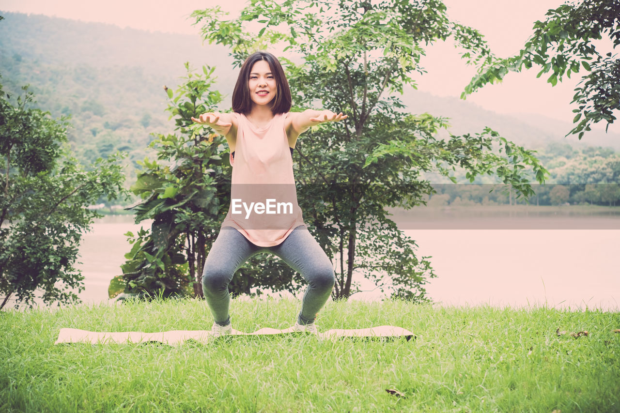Portrait of smiling woman exercising by lake