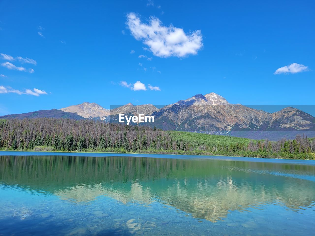 LAKE BY MOUNTAINS AGAINST BLUE SKY