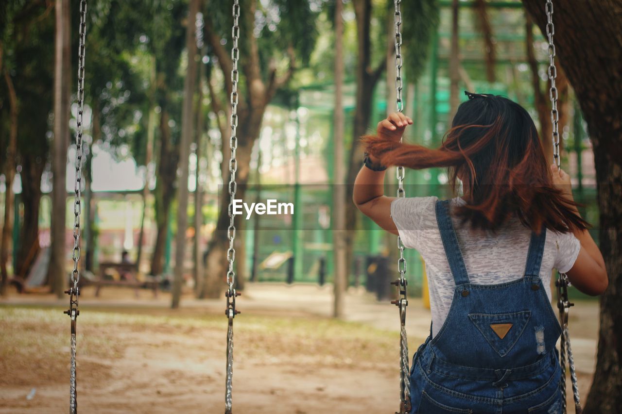 Rear view of woman sitting on swing in playground