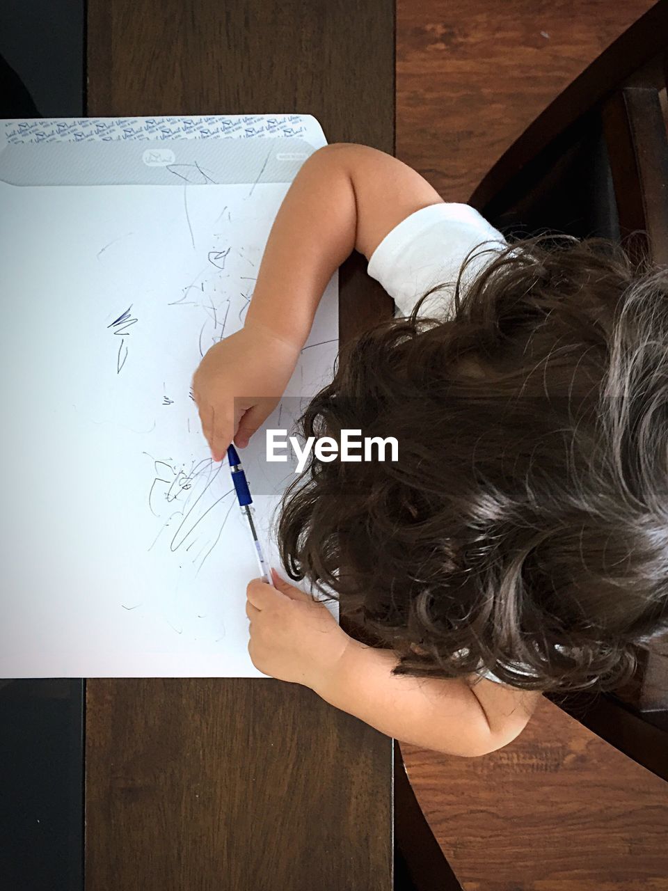 Overhead view of baby scribbling on paper at table