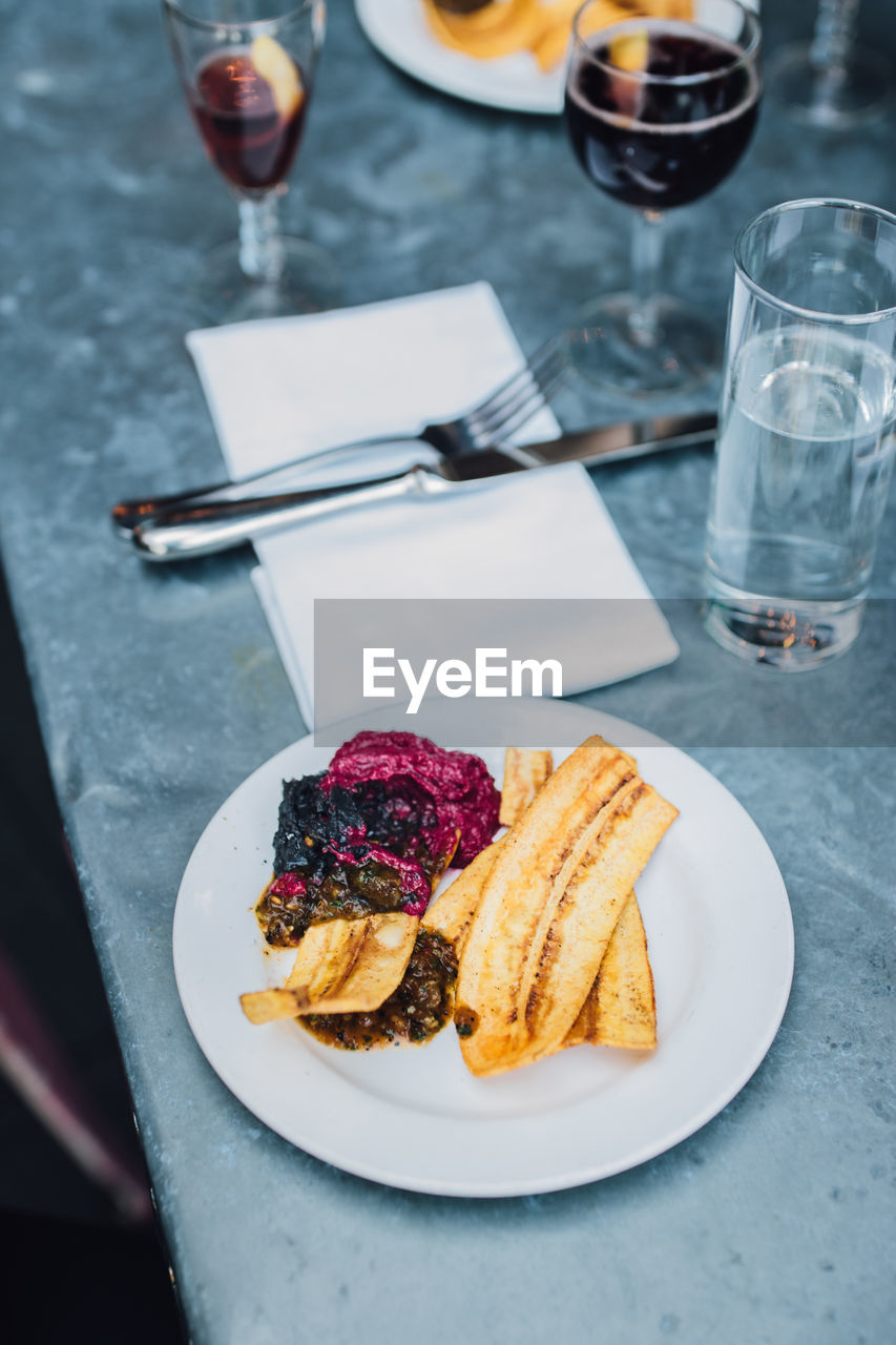 Plantain chips and dips at outdoor restaurant with red wine