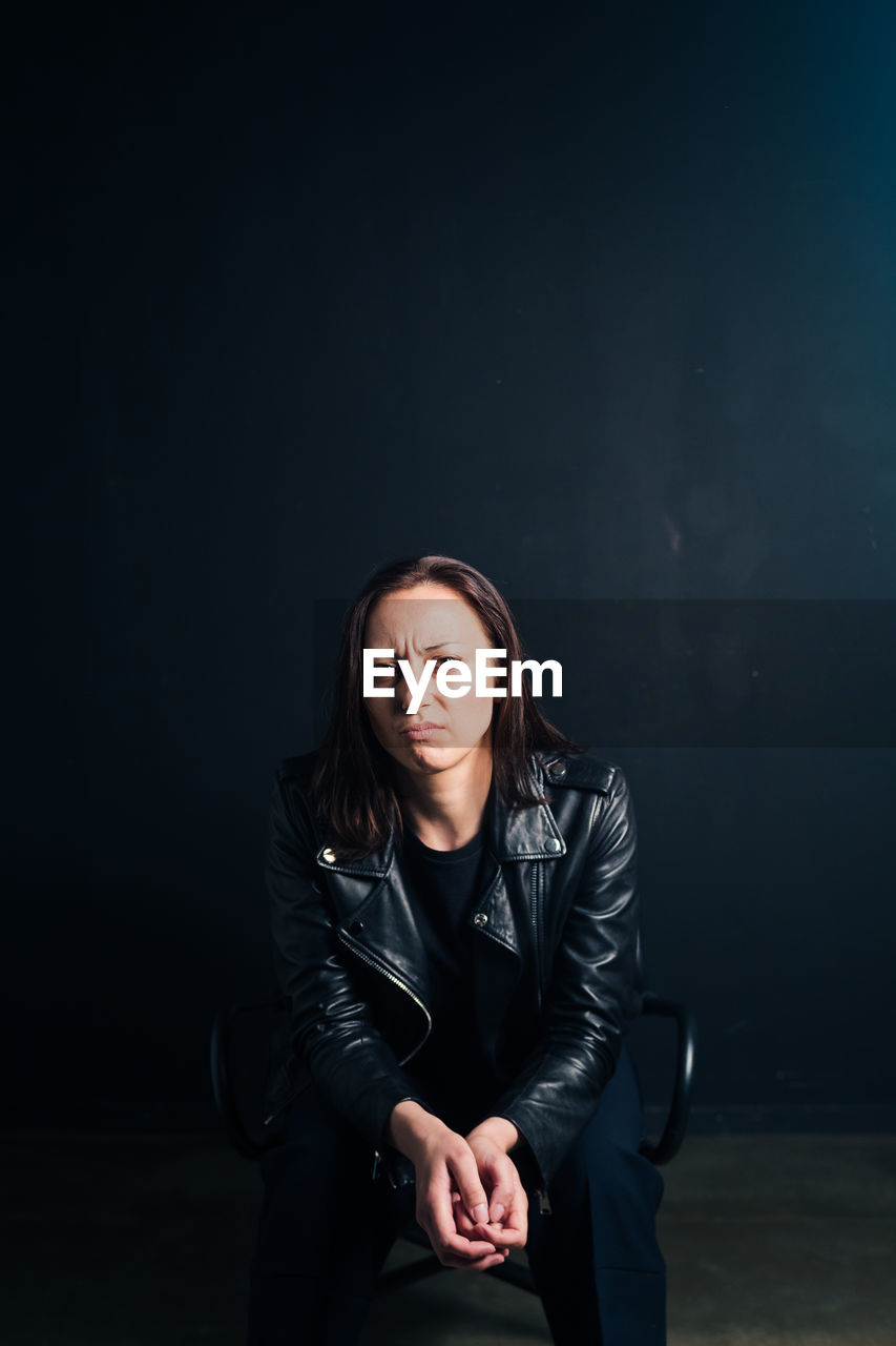 PORTRAIT OF WOMAN STANDING AGAINST BLACK BACKGROUND