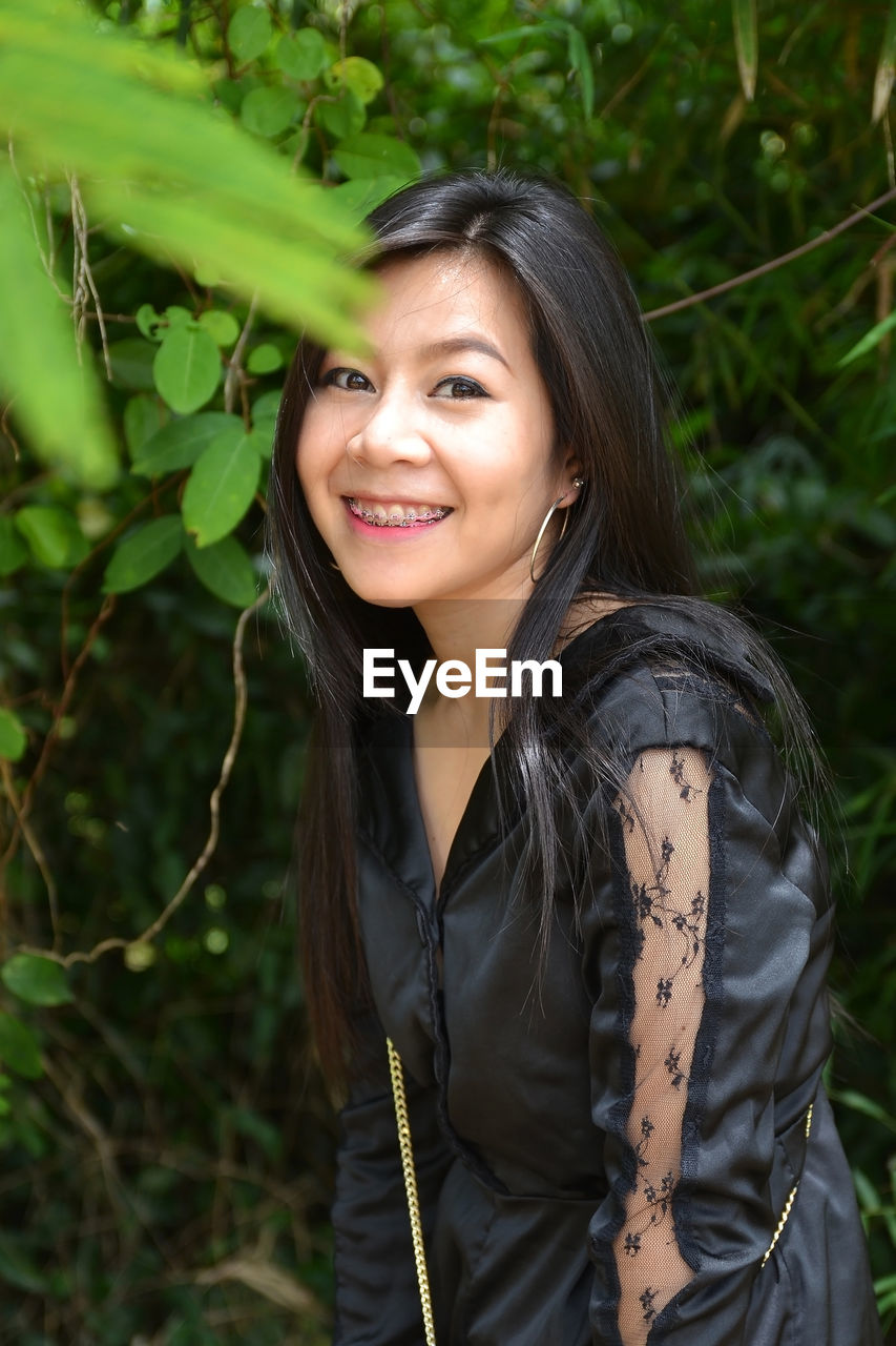 Portrait of smiling asian woman with dental braces system wearing a black dress