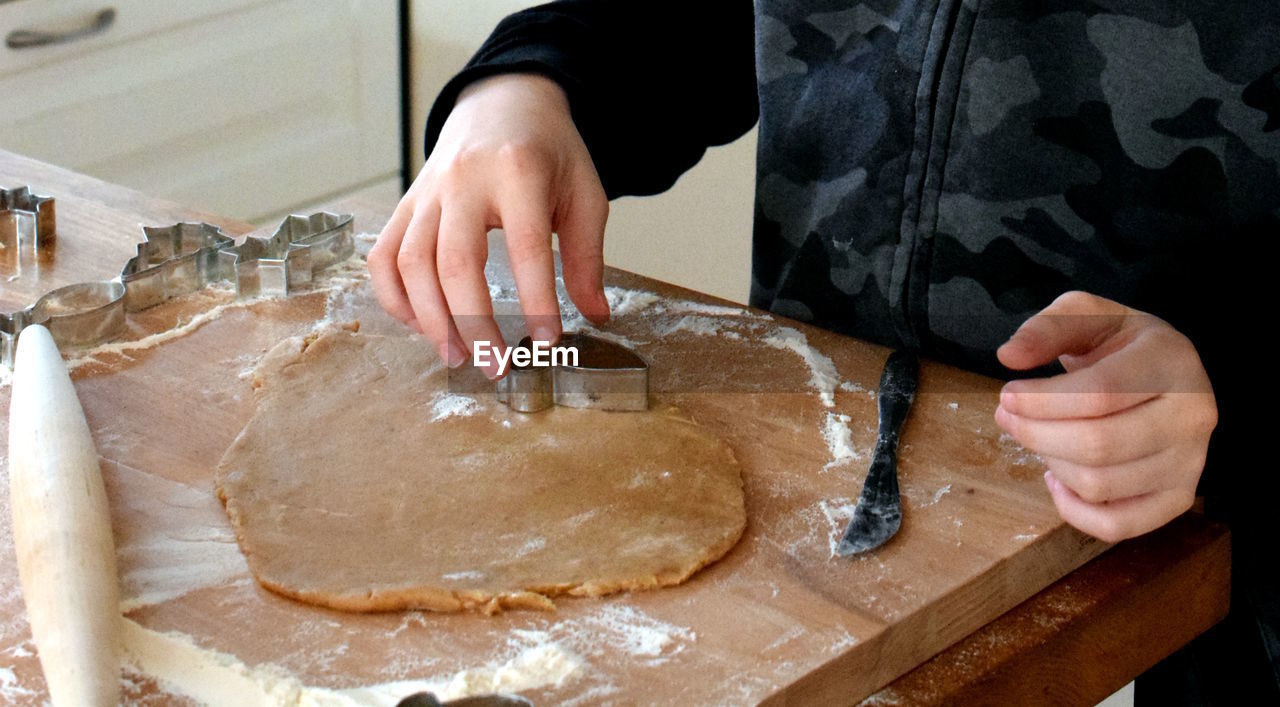 Midsection of person preparing gingerbread for christmas